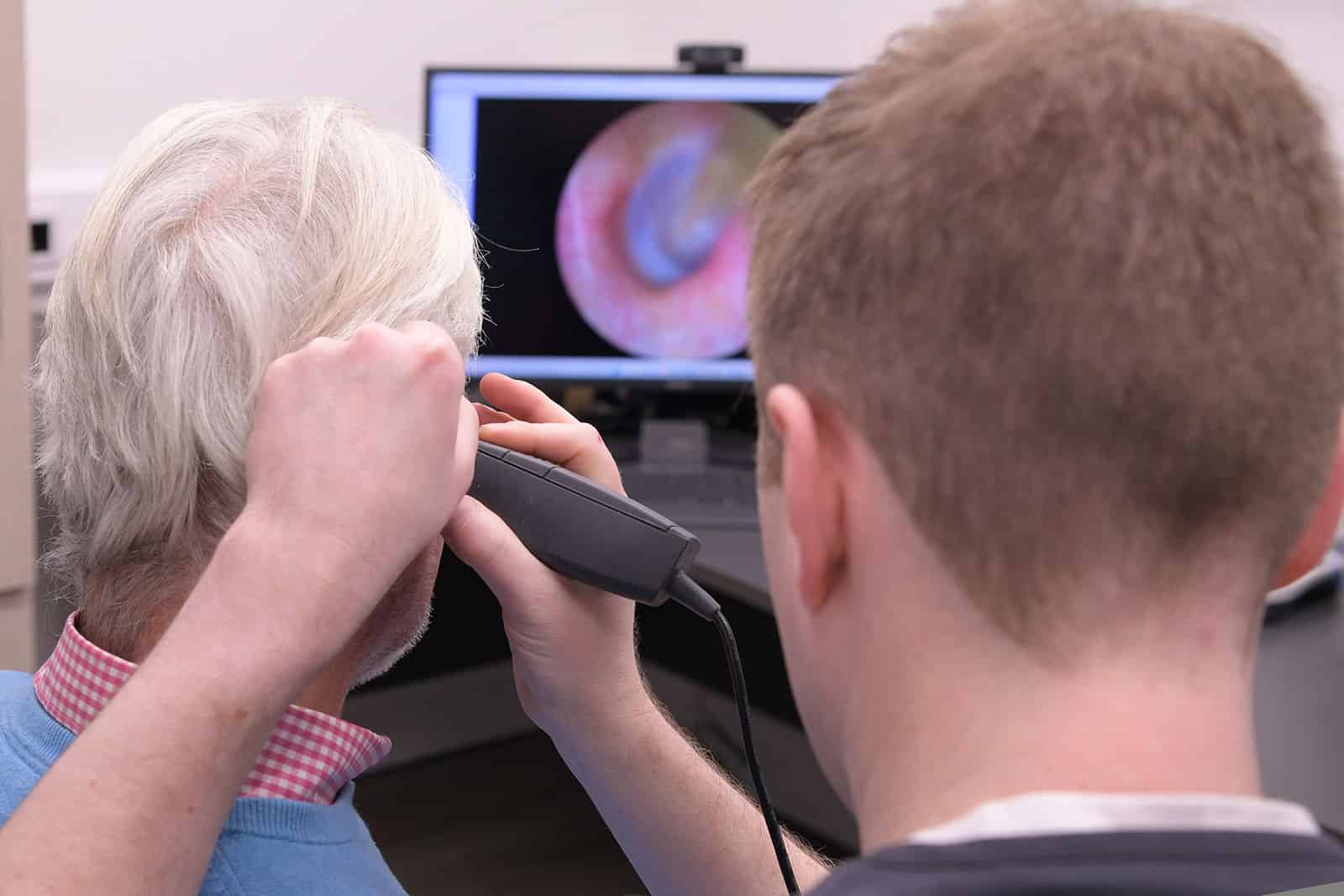 Audiologist completing otoscopy on a male customer