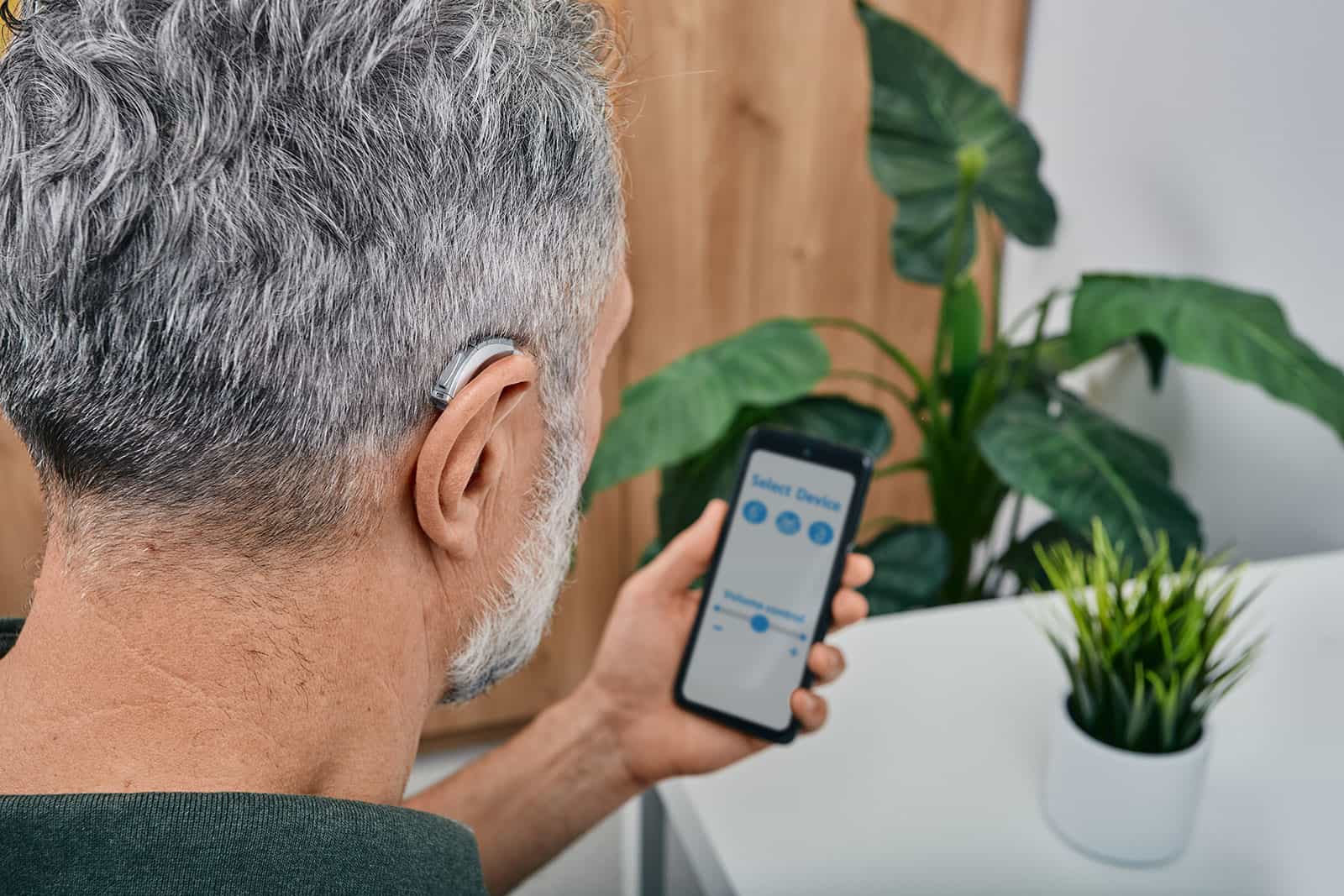 Man wearing hearing aid and using hearing aid app