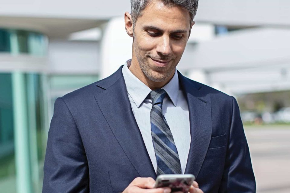 Man wearing hearing aids looking at his phone