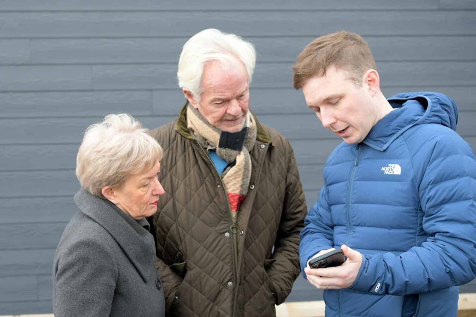 Audiologist demonstrating a hearing aid app to a couple outside