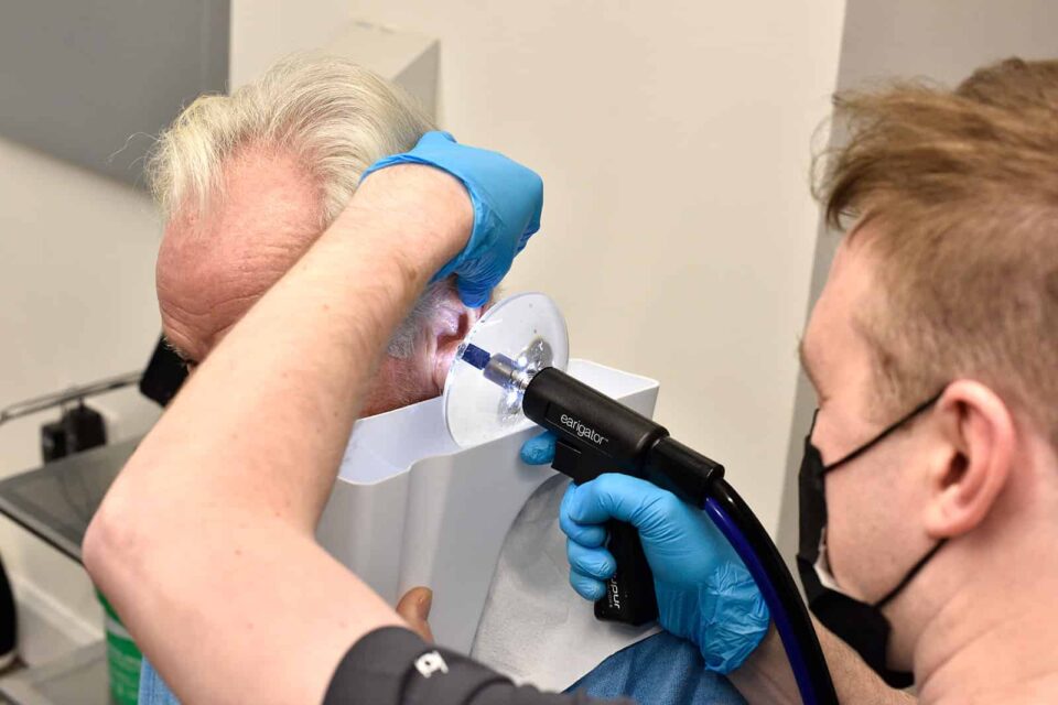 Audiologist completing ear wax removal on a male customer