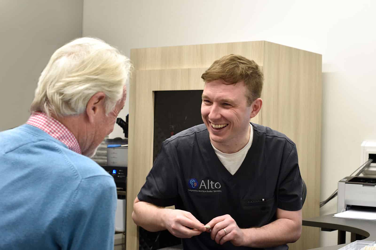 Audiologist demonstrating a hearing aid to a male customer