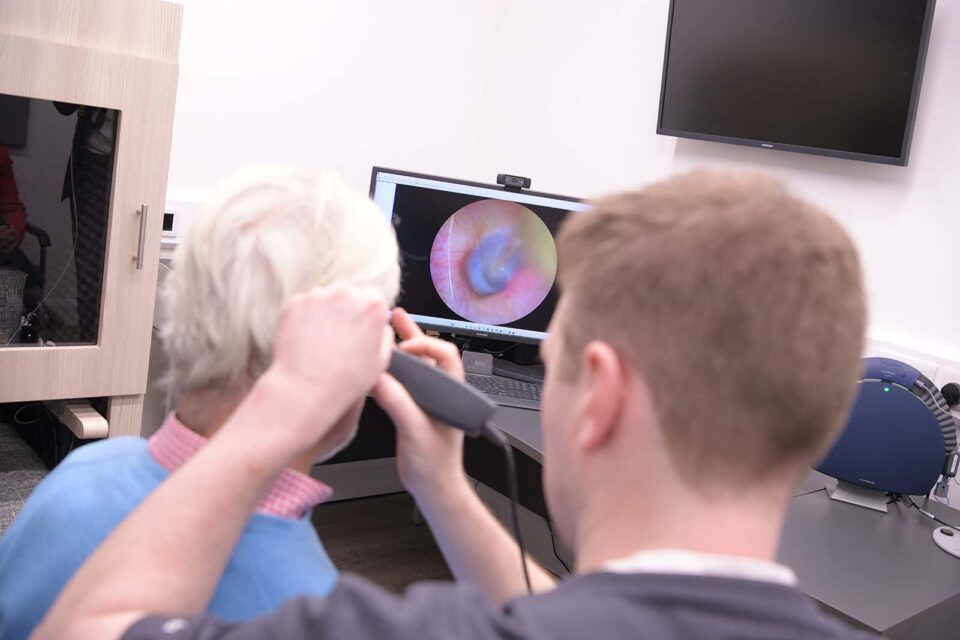 Audiologist completing otoscopy on a man