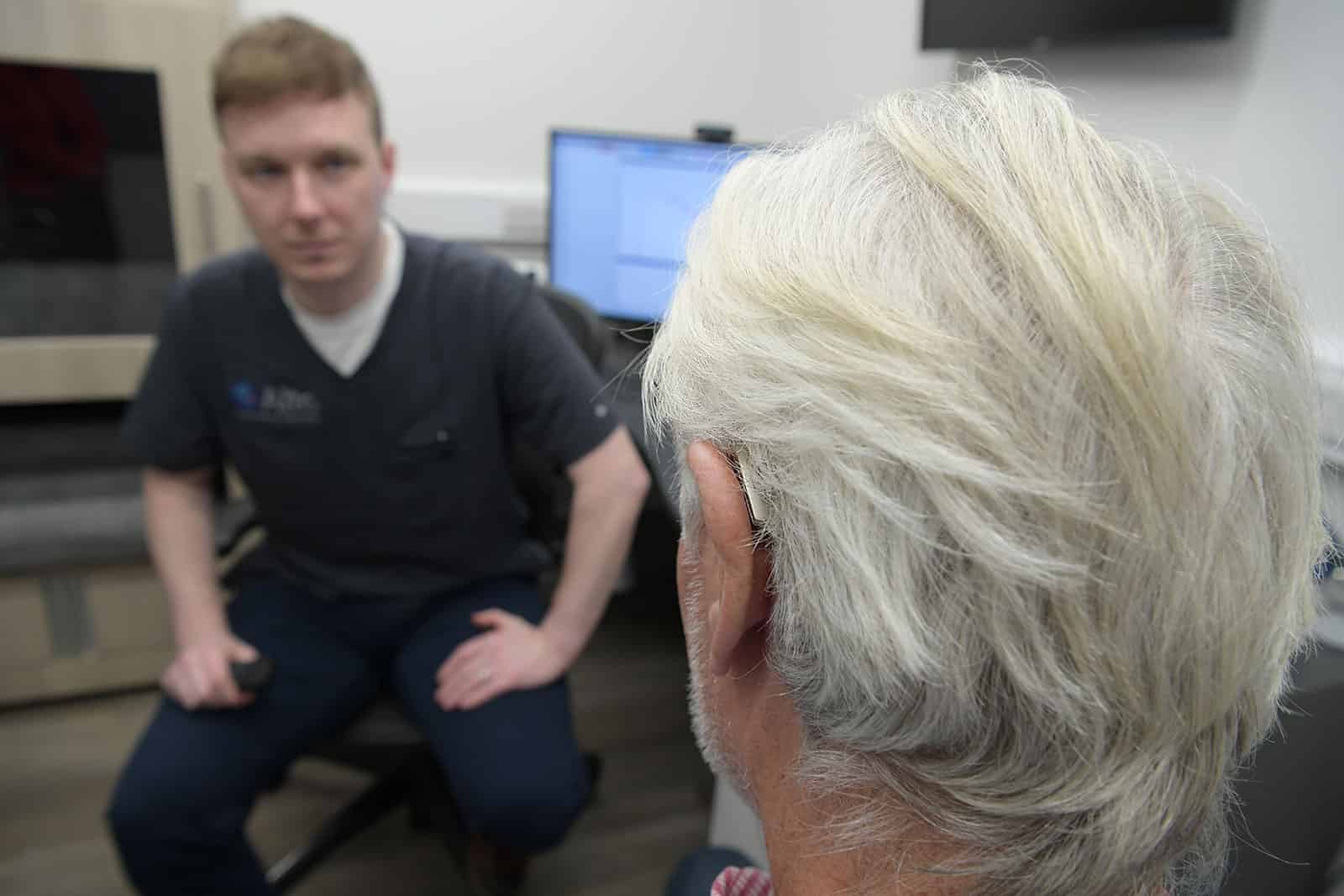 Audiologist speaking with a male customer who is wearing a hearing aid