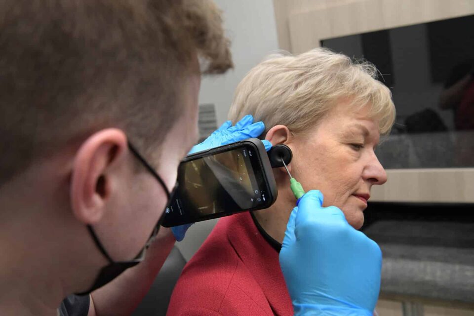 Audiologist performing microsuction ear wax removal on a female customer