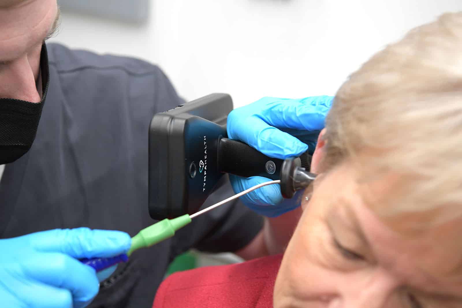 Audiologist performing microsuction ear wax removal on a female customer